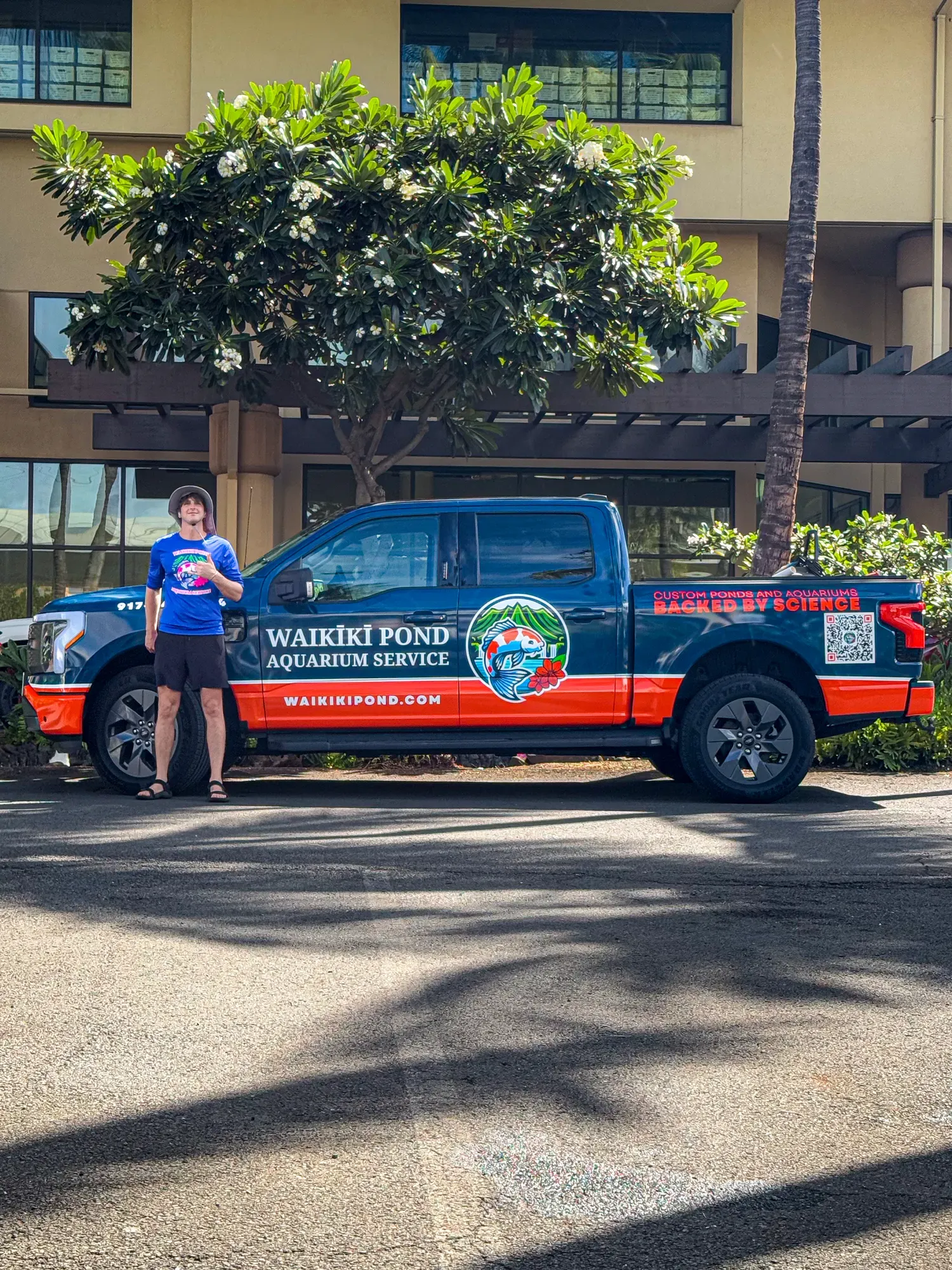 The owner in a branded shirt alongside the truck, showing the vehicle wrap and the uniform as one system.